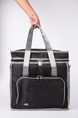 Black and gray tote bag held by a person on a white background
