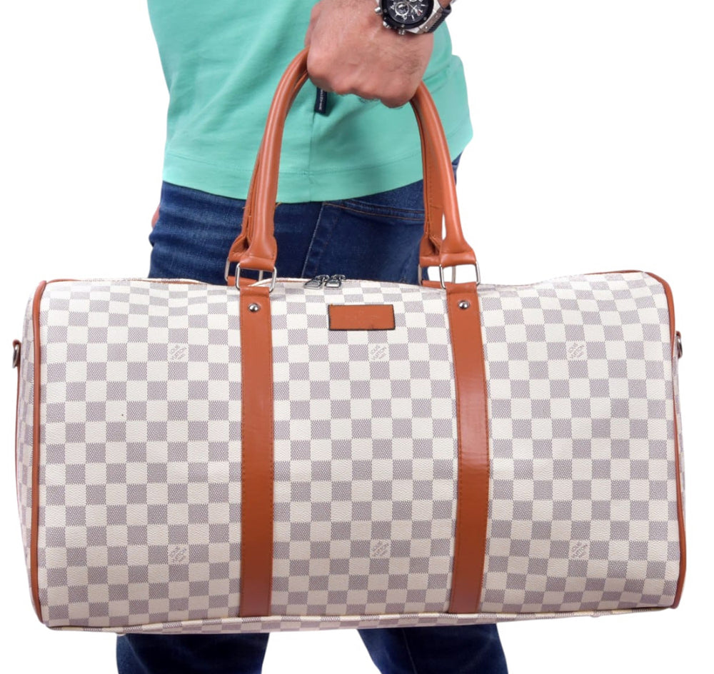 Checkered duffel bag with brown straps held by a person wearing a turquoise shirt.